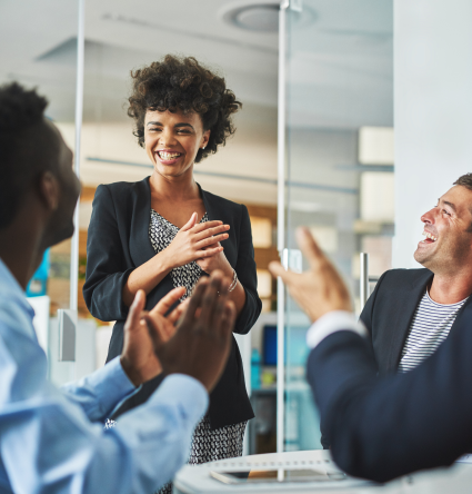 Three business people laughing around a table.